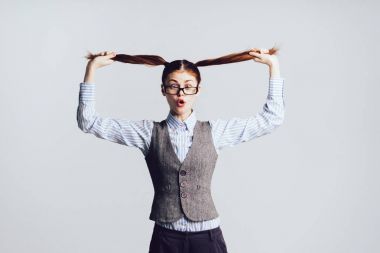 gözlüklü kız onun kuyrukları onun elinde tutar ve kamera hayretle bakar