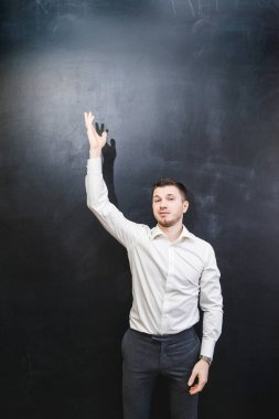 Beyaz gömlekli bir genç adam büyük Kurulu tarafından duruyor ve elini yukarı kaldırdı