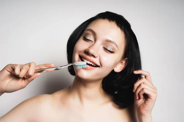 Menina feliz com cabelo preto escova os dentes, isolado — Fotografia de Stock