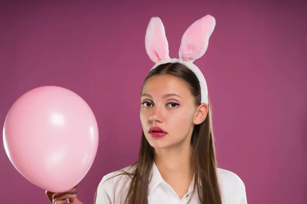 Ragazza carina e bella con le orecchie rosa in testa con una palla gonfiabile e guardando la fotocamera — Foto Stock