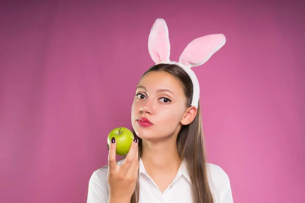 Härlig tjej med överliggande öron på huvudet äta ett äpple och tittar på kameran — Stockfoto