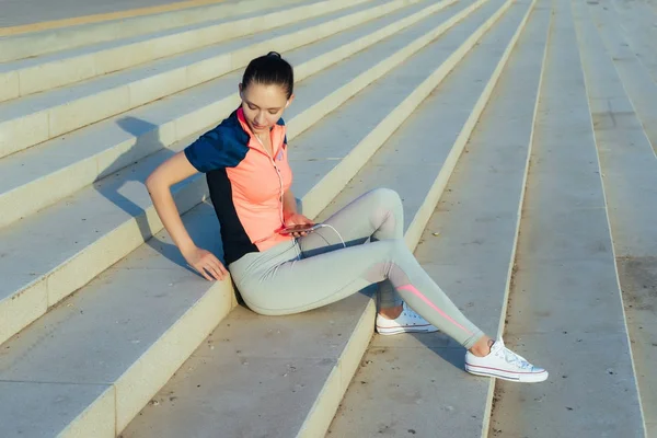 Dziewczyna w odzieży sportowej po joggingu przykucnął na schodach — Zdjęcie stockowe