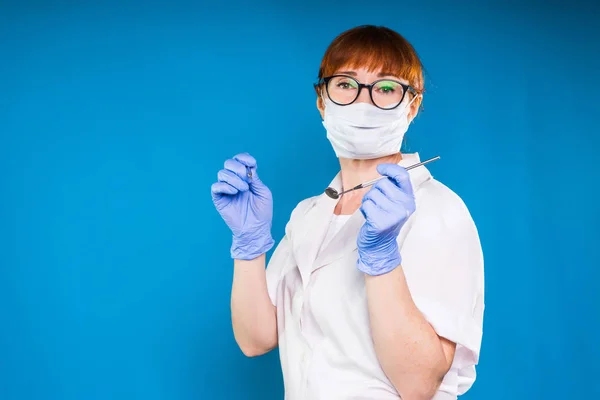 Kvinna i medicinska kläder och glasögon hålla ett medicinska instrument och tittar på kameran — Stockfoto