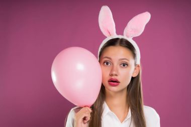 pembe kulaklı bir pembe top elleri ve sürpriz bir şey tutan güzel kız