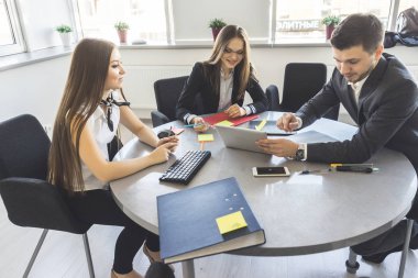 Ofis çalışanları bir masada oturup iş fikirleri tartışmak. Takım elbiseli genç adam tablet vasıl görünüyor
