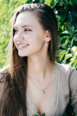 Gülümseyen ve uzağa bakarak bir ağaç arka plan bir yolda sevimli bir kız