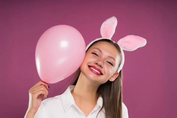 可爱的小女孩粉红色的耳朵持有一个粉红色的球，微笑着，看着相机 — 图库照片