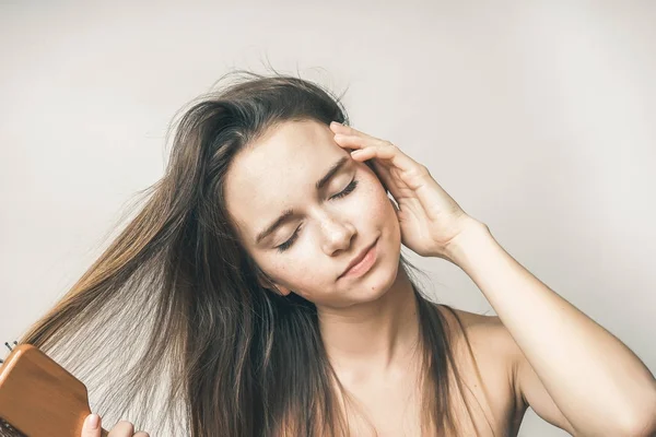 Mulher feliz penteando cabelos com pente. linda menina de cabelos longos fechou os olhos, isolado — Fotografia de Stock