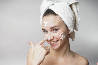 komik kadın mutlu kafasına bir havlu izole beyaz bir arka plan üzerinde köpük ile cildi temizler. Cilt Bakımı temizlik kavramı