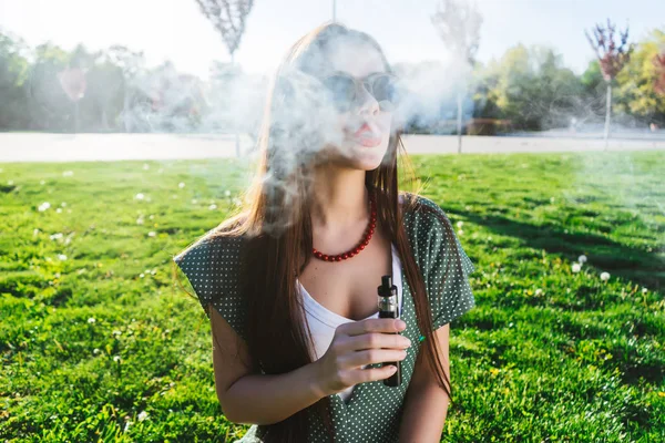 Feliz moda sonriente Mujer en gafas de sol fumar vapor en la calle, humo — Foto de Stock