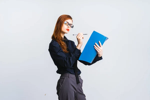 Junges schönes Mädchen mit langen roten Haaren in Brille hält in der Hand einen Ordner mit Dokumenten und einem Stift — Stockfoto