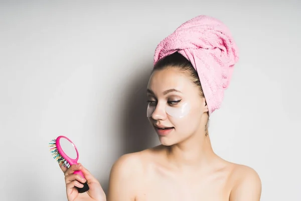 Όμορφη κοπέλα με καθαρό δέρμα και ένα ροζ πετσέτα χαμογελαστός και να κοιτάξουν στον καθρέφτη — Φωτογραφία Αρχείου