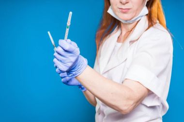 yetişkin kadın doktor koruyucu maske ve beyaz tıbbi sabahlık şırınga tutar