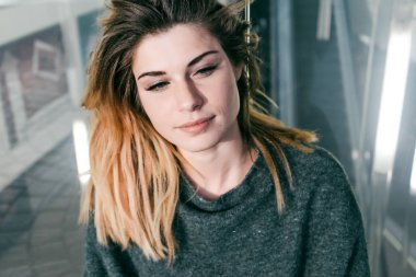 genç güzel kız kalın saç ile oturur ve gülümsüyor ve tepeden bakıyor