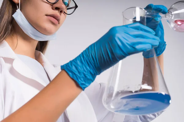 안경에 흰색 의료 장갑 젊은 아름 다운 소녀 의사 혼합 화학 물질을 플라스 크에 — 스톡 사진