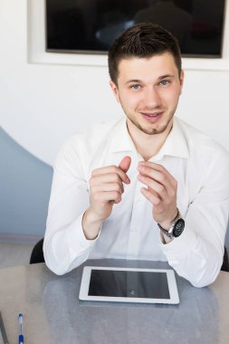 Tablo, ofiste oturmuş sakallı genç yakışıklı başarılı adam gülümseyen