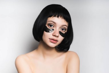 kısa siyah saçlı, Siyah Silikon yamalar gülümseyen gözleri altında genç güzel kız