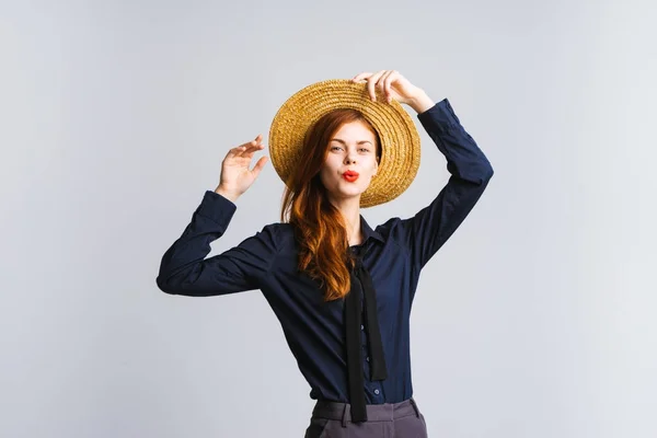 Giovane bella ragazza con i capelli rossi in un cappello di paglia tiene le mani — Foto Stock
