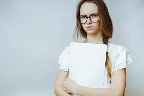 Junges trauriges Mädchen mit Brille und langem Haar hält weiße Papiere in der Hand — Stockfoto