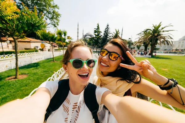 Dos novias sonrientes con sonrisas de dentista blanco hacen selfie. Diferentes nacionalidades, personas de amistad — Foto de Stock