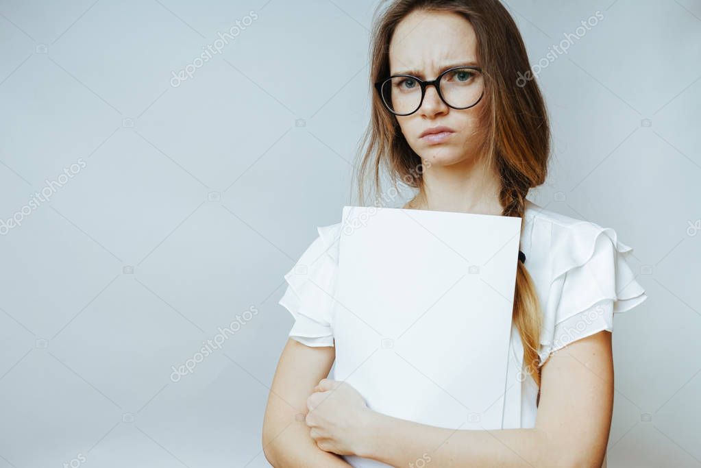 young sad girl with glasses and with long hair is holding white papers