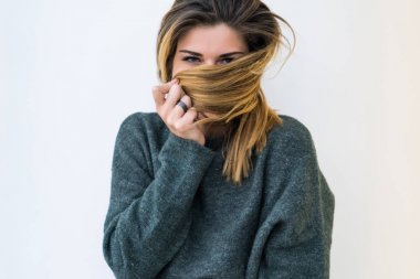 Kız büyük bir gri süveterli yüzünü saçlarını izole kapsar.