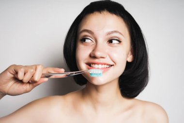 onun diş fırçalama ve flirtatiously uzak seyir siyah kısa saçlı güzel kız