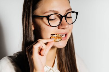 Genç modern başarılı iş kadını ile gözlük, bir altın bitcoin onun elinde tutan ve tadı