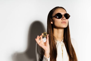 güneş gözlüklü genç modern başarılı iş kadını elleri Kripto para birimi hakkında düşünüyor bir altın bitcoin tutar