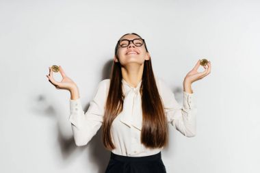 Gözlüklü genç modern başarılı iş kadını altın bitcoins tutar ve mutlu görünüyor
