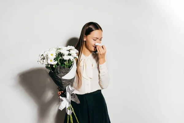 Joven hermosa chica sosteniendo un gran ramo de flores blancas en sus manos y estornudos porque es alérgica a las flores — Foto de Stock