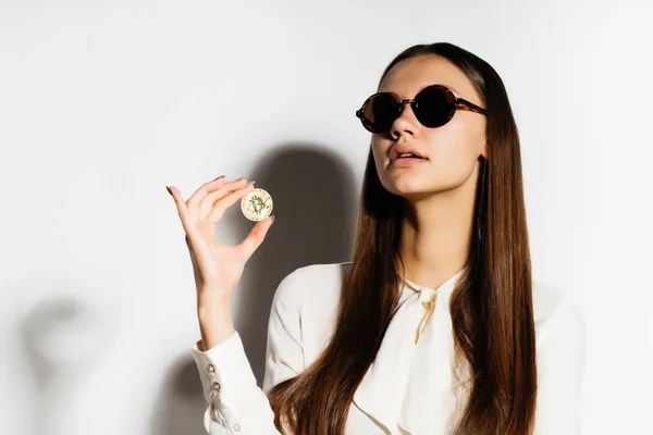 Jovem mulher de negócios bem sucedida moderna em óculos de sol, segura em mãos um bitcoin dourado — Fotografia de Stock