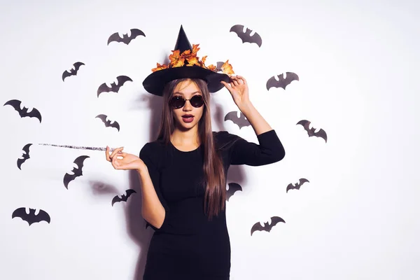 Joven hermosa chica gótica sexy en gafas de sol se convirtió en una bruja para Halloween, tiene en sus manos una varita mágica —  Fotos de Stock