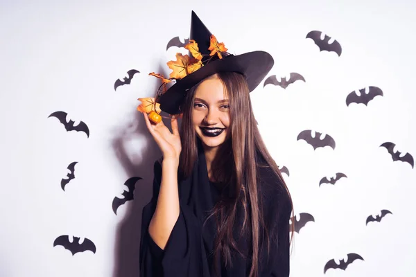 Een jonge sexy gothic meisje viert halloween, gekleed in een heks, volledig zwarte kleding, lacht — Stockfoto