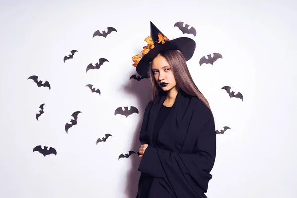 Een jonge sexy gothic meisje viert halloween, gekleed in een heks, volledig zwarte kleding, poses — Stockfoto