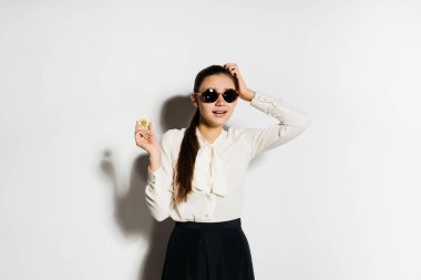 güneş gözlüklü genç başarılı modern kız altın bitcoin elinde tutar.