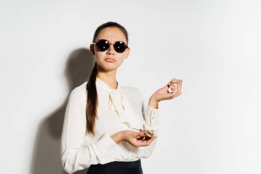 güneş gözlüklü genç başarılı modern kız altın bitcoin elinde tutar.