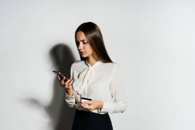 bir banka kartı ve akıllı telefon elinde tutan genç başarılı modern kız