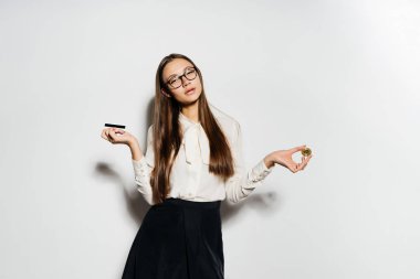 Gözlüklü genç başarılı modern kız altın bir bitcoin ve bir banka kartı elinde tutuyor
