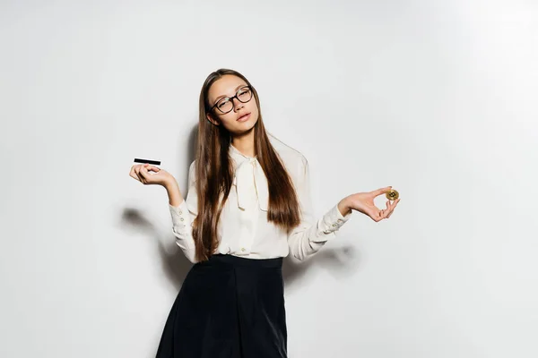 Una joven exitosa chica moderna con gafas tiene un bitcoin de oro y una tarjeta bancaria en su mano — Foto de Stock