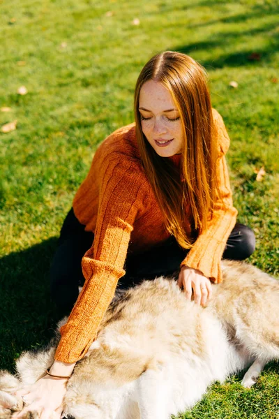 Unga vackra rödhåriga flickan gå med hennes stora grå hund i parken — Stockfoto