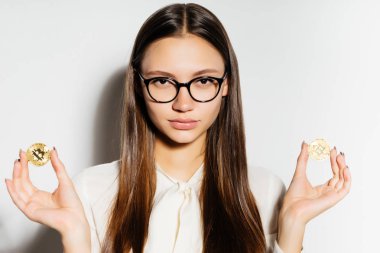 Gözlüklü genç başarılı modern kız altın bitcoins onun elinde tutuyor