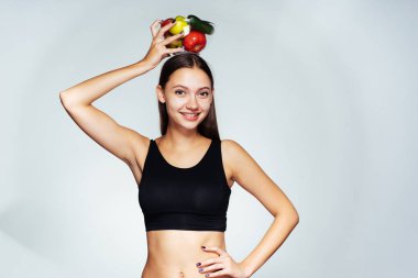 Siyah top bir genç atletik kız onu rakam tutar, bir tabak yararlı sebze ve meyve ile onun elinde tutan