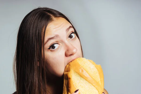 Krásná mladá dívka chce zhubnout, dychtivě jí škodlivé vysokokalorickou bílý chléb — Stock fotografie
