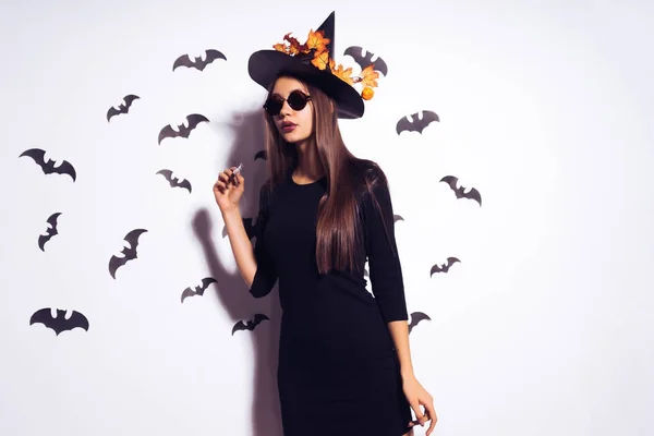 젊은 섹시 한 고딕 소녀 할로윈, 마녀, 노란 단풍으로 장식 된 큰 검은 모자에 선글라스를 쓰고 옷을 입고 기념 — 스톡 사진