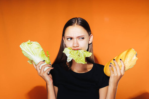 a young beautiful girl wants to lose weight, eats useful Peking cabbage, holds in her hand harmful calorie white bread