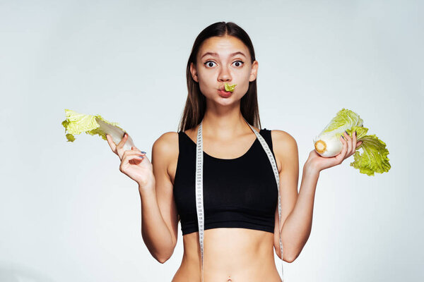 a young athletic girl in a black top keeps track of her figure, holds a useful Peking cabbage