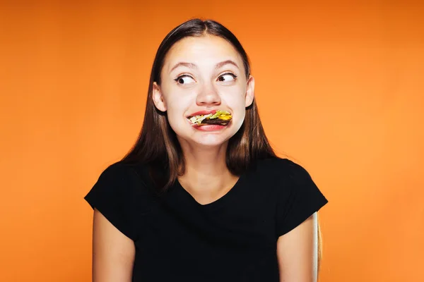 Junges schönes Mädchen will abnehmen, isst aber eifrig einen schädlichen, kalorienreichen Burger — Stockfoto