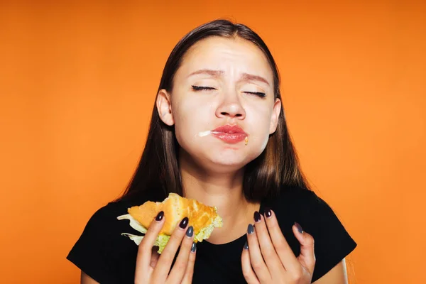 Genç güzel kız kilo vermek istiyor, ama hevesle zararlı yüksek kalorili hamburger yiyor — Stok fotoğraf