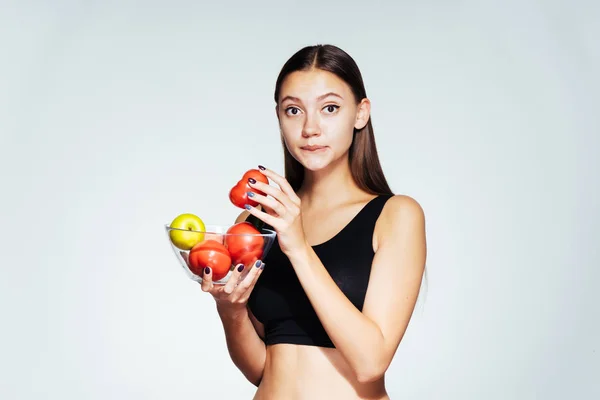 Sportovní dívka v černý top uchovává informace o její postavy, drží desku s užitečné zeleniny a ovoce ve svých rukou — Stock fotografie